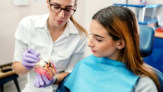 Patientin bekommt Modell eines Gebisses gezeigt